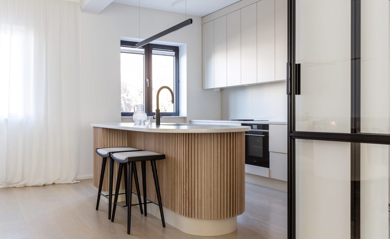 Kjøkkenet til Camilla Pihl er spesialbygd av møbelsnekker med fronter i grå beige tone og kjøkkenøy med runde kanter og spiler. Utført av Lomundal.