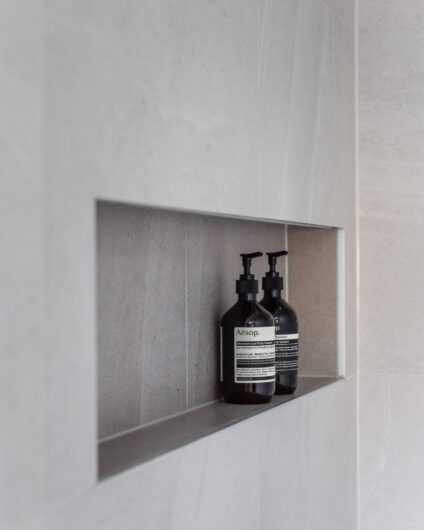 Detaljbilde av hyllenisje i dusjrom med shampoo og balsam fra Aesop, utført av Lomundal.