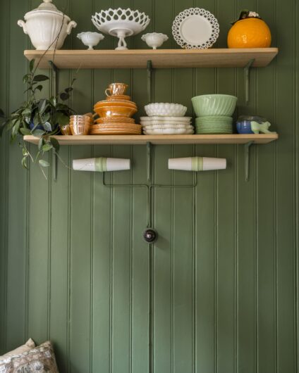 Detaljbilde fra kjøkken med mørk grønn vegg og hylle med dekorative skåler, utført av Lomundal.