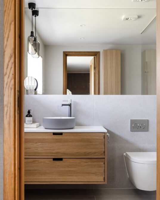 Bad med baderomsmøbel i eik, frittstående vask og grå fliser. Badet er utført av Lomundal.