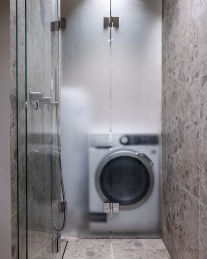 Praktisk løsning med vaskemaskin gjemt bak dør i frostet glass. Badet er totalrenovert av Lomundal.