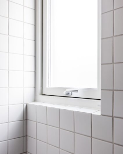 Detaljbilde av vindu på baderom med kvadratiske hvite fliser rundt. Badet er totalrenovert av Lomundal.