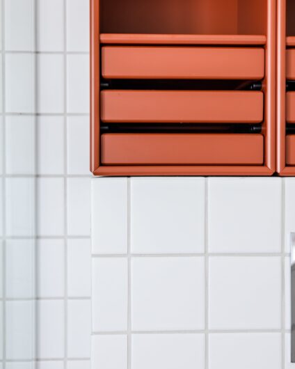 Detaljbilde fra retro bad med kvadratiske hvite fliser på vegg med veggmontert innredning fra Montana i rød. Utført av Lomundal.