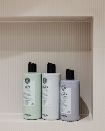 Detaljbilde av shampoo og balsam fra Maria Nila som står i innebygd hyllenisje i dusj. Badet er pusset opp av Lomundal.
