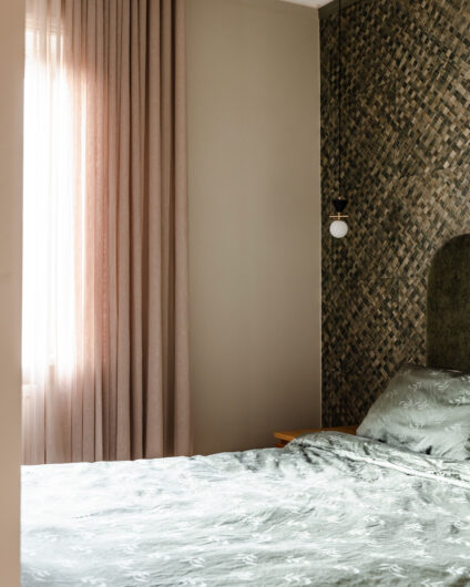 Soverom med grønn tapet på vegg med tekstur. Matchende sengetøy i en lys grønntone og lyse gardiner. Totalrenovert av Lomundal.