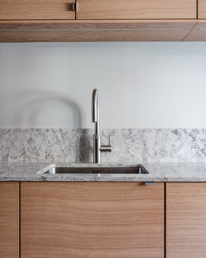 Detaljbilde fra kjøkken i eik fra Drømmekjøkkenet med grå og hvit benkeplate i stein. Armatur fra Quooker. Utført av Lomundal.