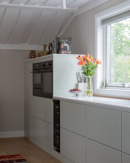 Lyst og moderne kjøkken i en lys grønn tone på frontene med en lys benkeplate. Lyse vegger og tak.