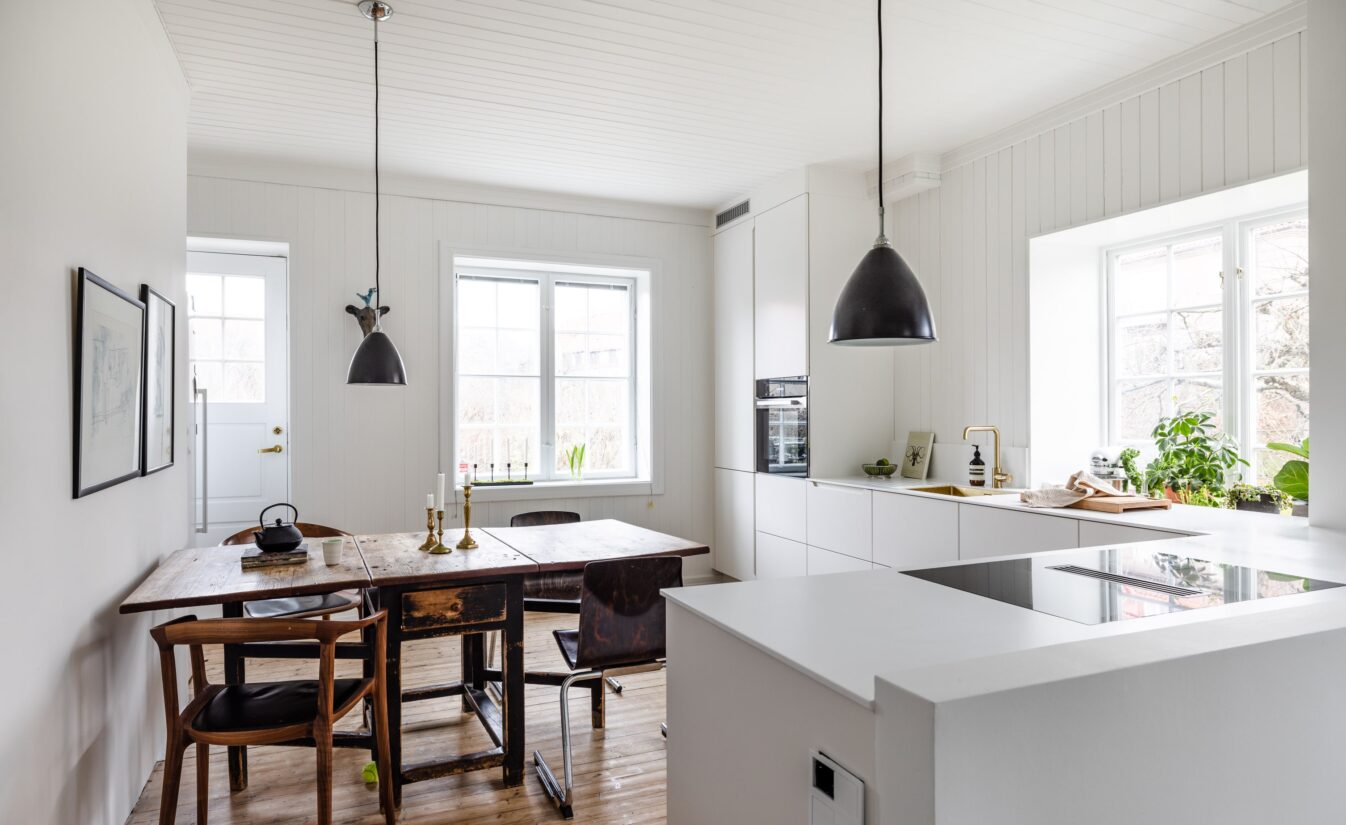 Lyst og moderne kjøkken fra Uniform i hus i Ullevål Hageby. Spisebord og stoler bryter opp og skaper fine kontraster i rommet.