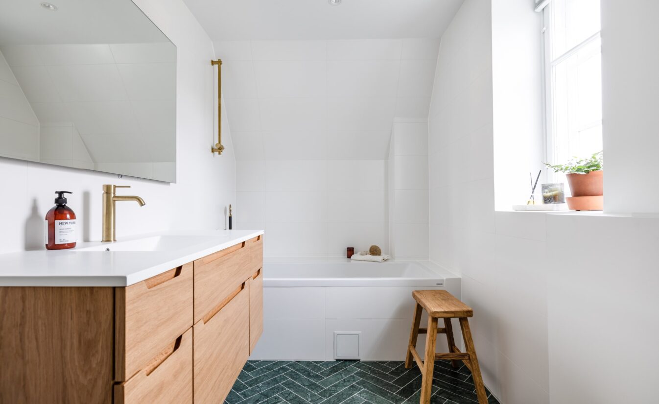 Moderne bad med grønne fliser på gulv og malte flater på vegg. Baderomsinnredning i eik fra Linn Bad.