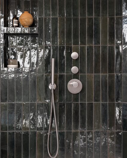 Detaljbilde fra dusjsone med grønne avlange fliser i blank finish med innebygde armaturer fra Dornbracht og hyllenisjer.