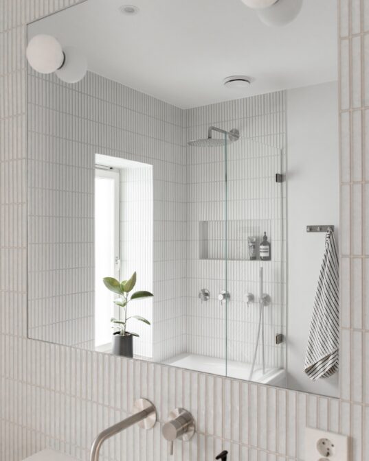 Lyst og moderne bad med avlang kitkat flis på vegg, innebygde armaturer i stål fra Qtoo. Badet er pusset opp av Lomundal.